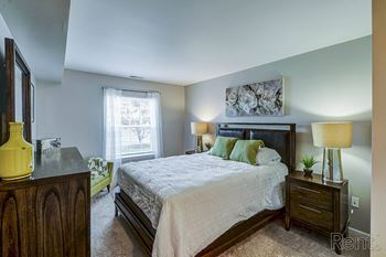 A bedroom with a large bed, wide window with curtains